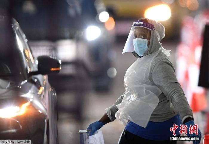 當?shù)貢r間12月18日，英國政府公布的數(shù)據(jù)顯示，當天英國新增奧密克戎毒株感染病例10059例。鑒于奧密克戎毒株感染病例激增，住院人數(shù)不斷上升，倫敦市長宣布倫敦進入“重大事故”狀態(tài)。圖為倫敦的一個免下車檢測中心，一名醫(yī)務工作者正準備對司機進行核酸檢測。