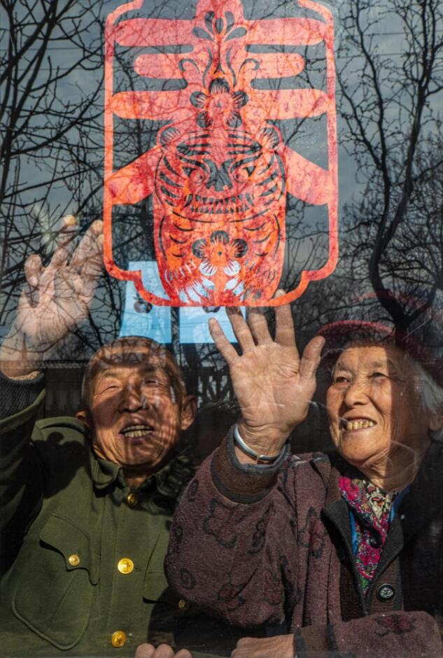 臘月里，霍州市師莊鄉(xiāng)馮南垣村村民師榮光(左)在災后重建的新家里貼窗花。(霍州市委宣傳部供圖)