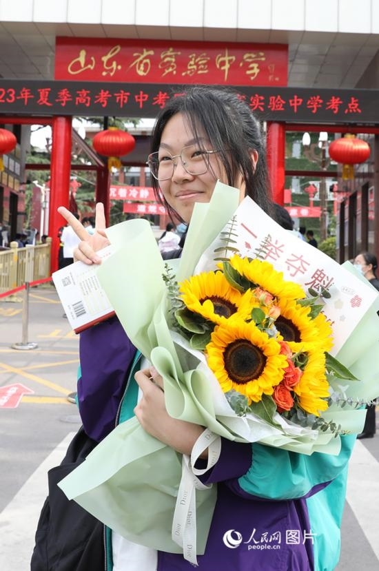 6月7日高考首日，山東67萬考生走進考場，拼搏逐夢。在山東省實驗中學考點，考生進考場前手捧向日葵花拍照留念，寓意“一舉奪魁”。人民網記者 劉祺攝