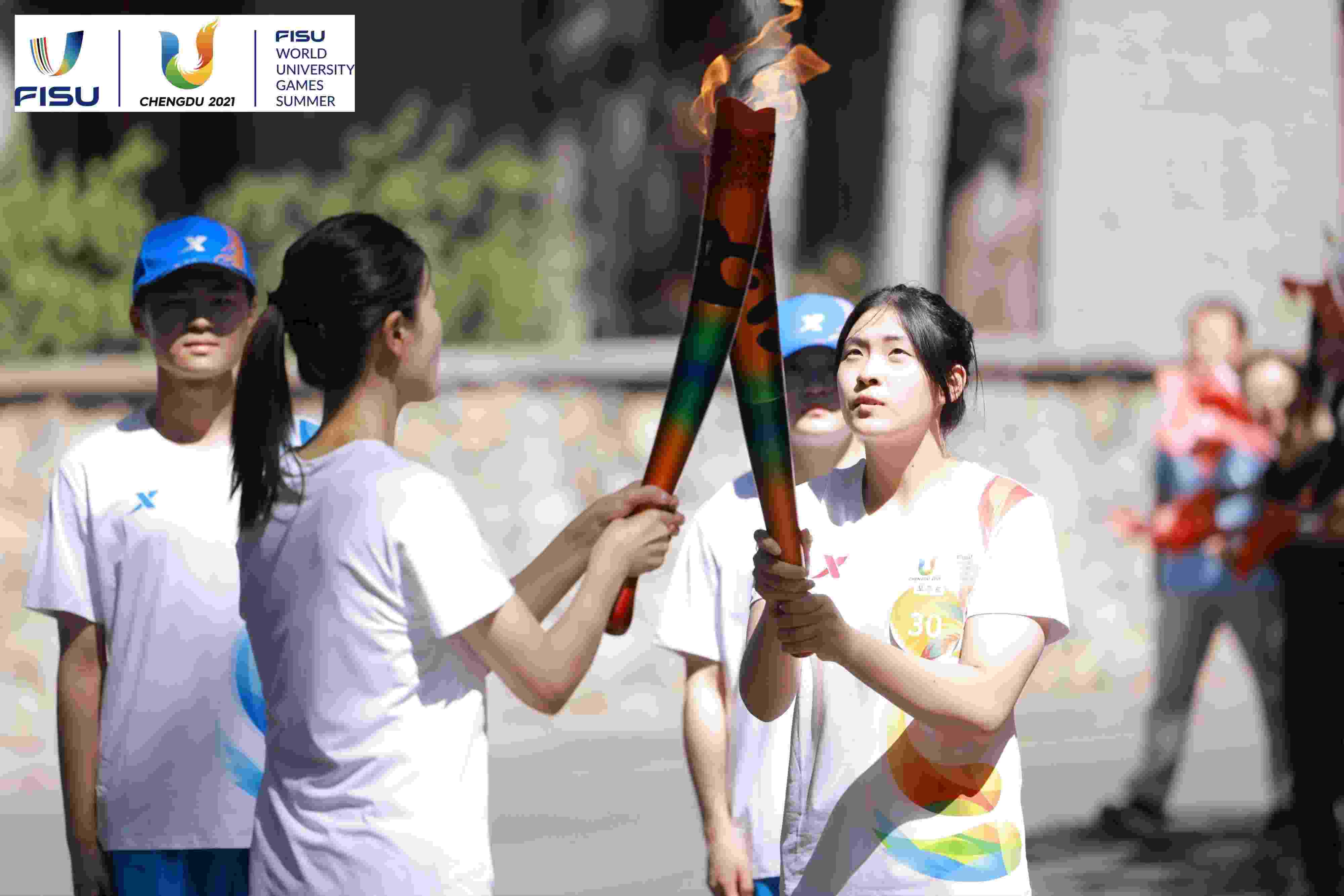 兩名大運(yùn)會(huì)火炬手進(jìn)行火炬?zhèn)鬟f。 圖片來源：成都大運(yùn)會(huì)執(zhí)委會(huì)供圖