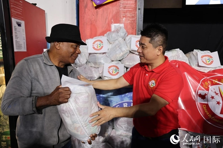巴西中國(guó)浙江商會(huì)會(huì)長(zhǎng)鄭俠茂向社區(qū)居民轉(zhuǎn)交捐贈(zèng)物資。人民網(wǎng)記者 時(shí)元皓攝