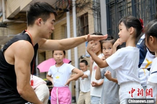 圖為大學(xué)生志愿者在組織孩子們參加體育健身活動(dòng)。廖光福 攝