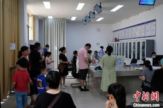 圖為在戶籍辦證廳內(nèi)排隊(duì)等待的家長(zhǎng)和孩子。劉俊聰 攝