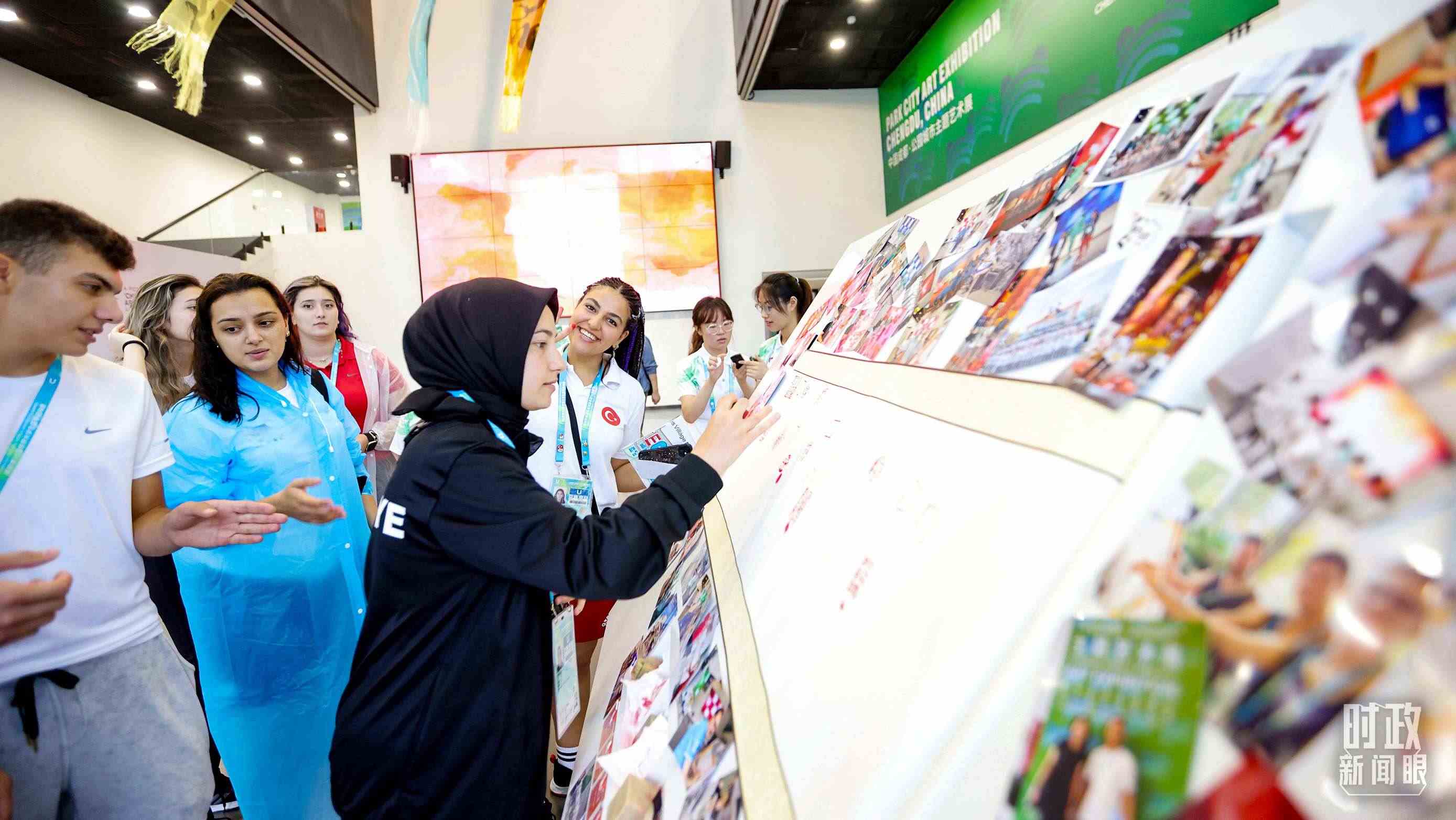 各國青年運(yùn)動員正在參觀成都大運(yùn)村內(nèi)的“雪山下的公園城市，煙火里的幸福成都”主題藝術(shù)展。（總臺央視記者魏幫軍拍攝）