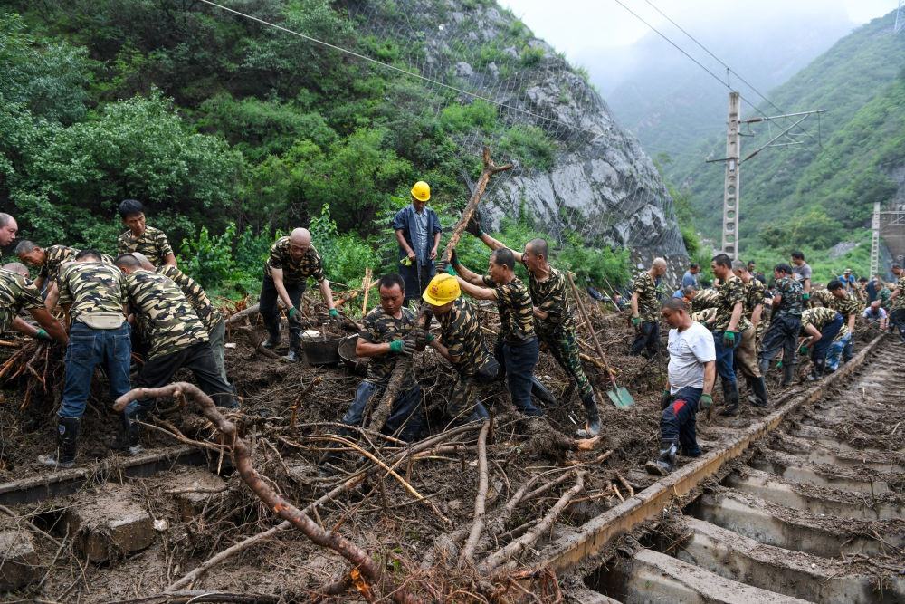 8月1日，在北京市門頭溝區(qū)水峪嘴村附近一段被阻斷的鐵路線上，中鐵六局工作人員在清理軌道上的雜物，全力恢復(fù)交通。新華社記者 鞠煥宗 攝