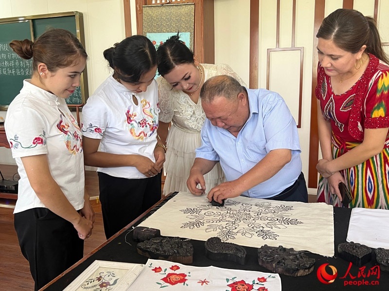 國家級非物質文化遺產模戳印花布技藝傳承人吾吉阿西木?吾舒爾展示模戳印花布的制作過程。人民網記者 常雪梅攝