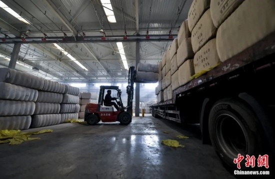 新疆喀什綜合保稅區(qū)，喀什啟路國際貿(mào)易有限公司的倉庫內(nèi)，工人正在裝載從塔吉克斯坦和烏茲別克斯坦進口的棉花。劉新攝