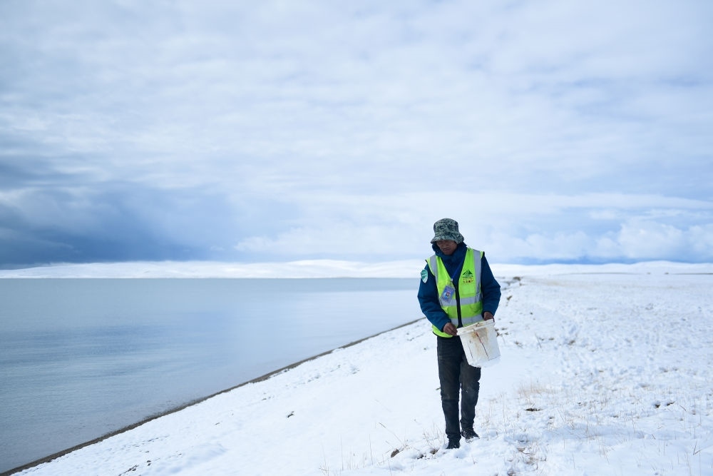 2021年10月20日，在青海省果洛藏族自治州瑪多縣扎陵湖鄉(xiāng)勒那村，三江源國(guó)家公園黃河源園區(qū)生態(tài)管護(hù)員在扎陵湖邊撿拾垃圾。新華社記者 張龍 攝