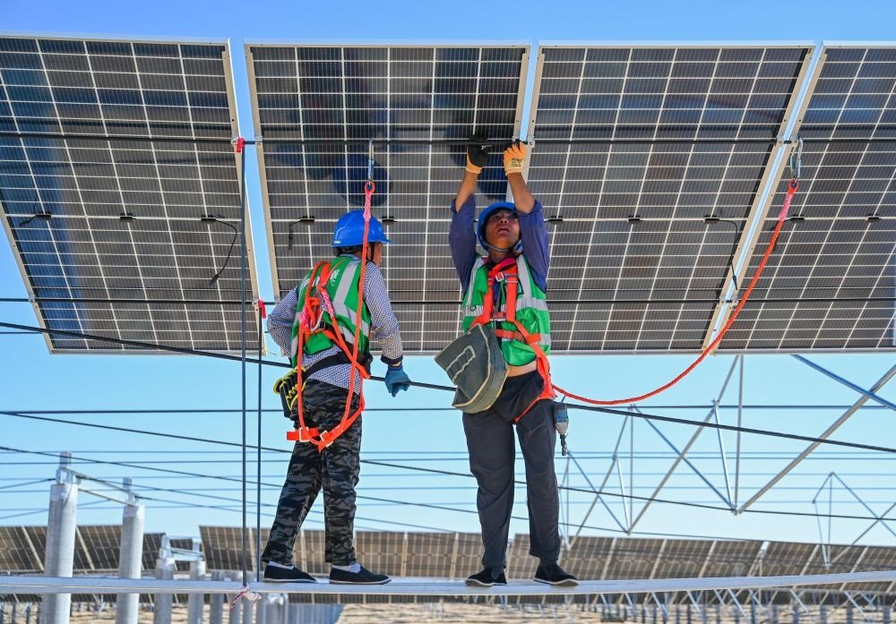 2023年7月22日，工人在位于內(nèi)蒙古杭錦旗庫(kù)布其沙漠億利生態(tài)示范區(qū)的蒙西基地庫(kù)布其200萬(wàn)千瓦光伏治沙項(xiàng)目工地安裝光伏板。新華社記者 劉磊 攝