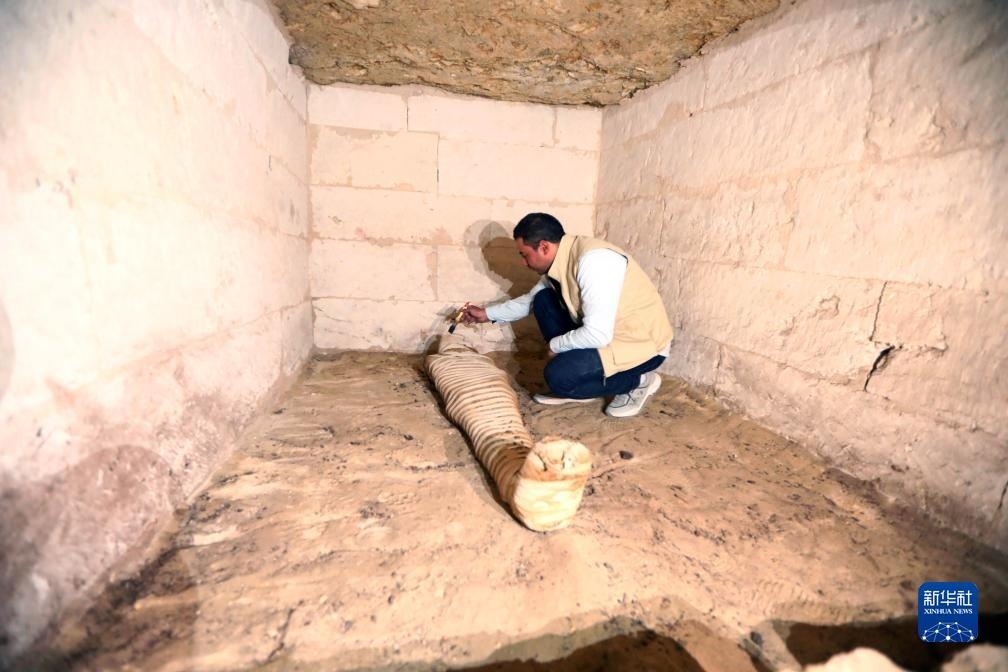 10月15日，在埃及明亞省考古現(xiàn)場(chǎng)，考古人員清理一座石鑿墓中的木乃伊。新華社發(fā)（艾哈邁德·戈馬攝）