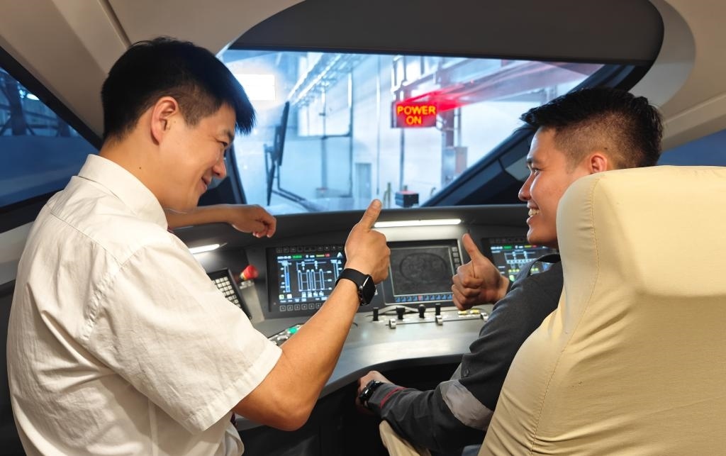 8月25日，在印度尼西亞萬隆的雅萬高鐵德卡魯爾動車所內(nèi)，中國師傅穆振（左）在向印尼火車司機(jī)塞蒂亞萬講解動車組出庫前的上電作業(yè)。