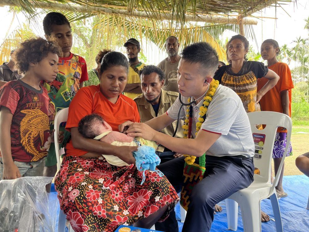 2023年8月5日，在巴布亞新幾內(nèi)亞中央省的一個村莊里，第12批援巴新中國醫(yī)療隊副隊長、新生兒科副主任醫(yī)師劉振球為嬰兒泰樂聽診檢查。泰樂出生時患有重癥，一度生命垂危，經(jīng)過劉振球與當(dāng)?shù)蒯t(yī)護人員的救治最終痊愈。從2002年起，中國連續(xù)向巴新派出12批醫(yī)療隊，為提高巴新醫(yī)療衛(wèi)生水平作出積極貢獻。