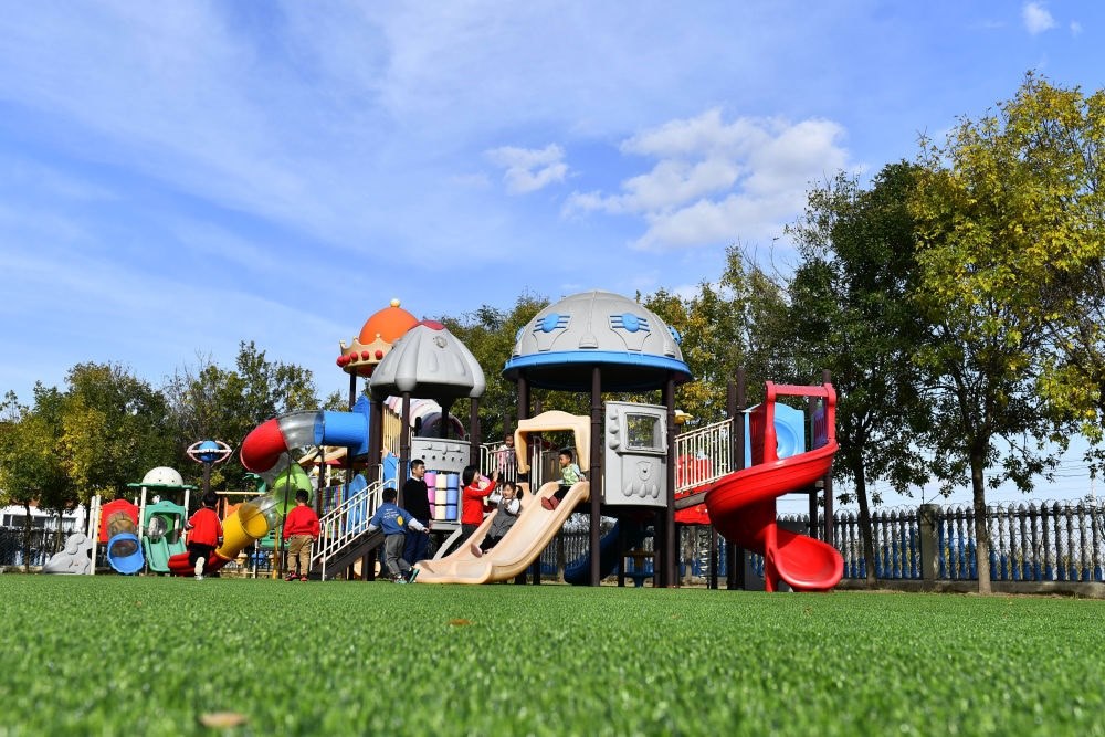 在山東省東營市墾利區(qū)楊廟社區(qū)幼兒園，孩子們在老師的帶領(lǐng)下進行戶外活動（2021年10月19日攝）。新華社記者 郭緒雷 攝