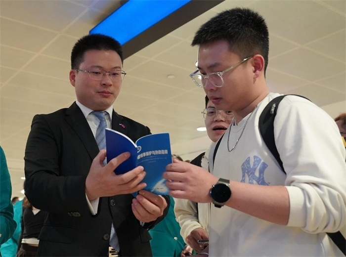 工作人員（左一）在發(fā)放《中國(guó)領(lǐng)事保護(hù)與協(xié)助指南》。 中國(guó)駐迪拜總領(lǐng)事館供圖