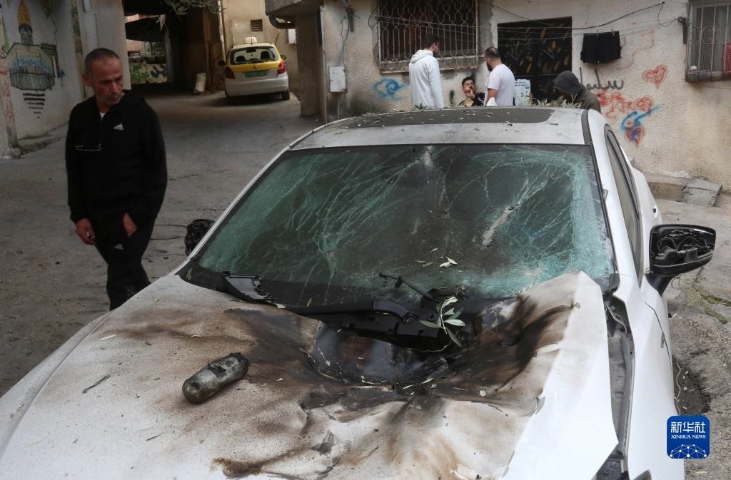 12月17日，在約旦河西岸城市圖勒凱爾姆附近的一處難民營，人們查看在沖突中損毀的車輛。新華社發(fā)（尼達爾·艾仕塔耶攝）