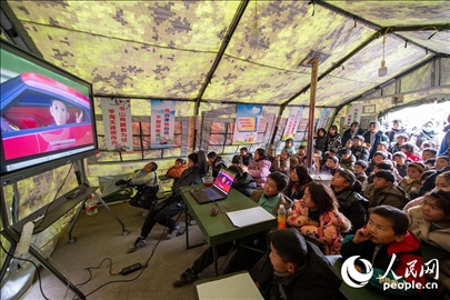 12月22日，在積石山縣大河家鎮(zhèn)大河村安置點，陸軍76集團(tuán)軍某旅搭建的“臨時學(xué)?！眱?nèi)，小朋友正在看動畫片。人民網(wǎng)記者 翁奇羽攝