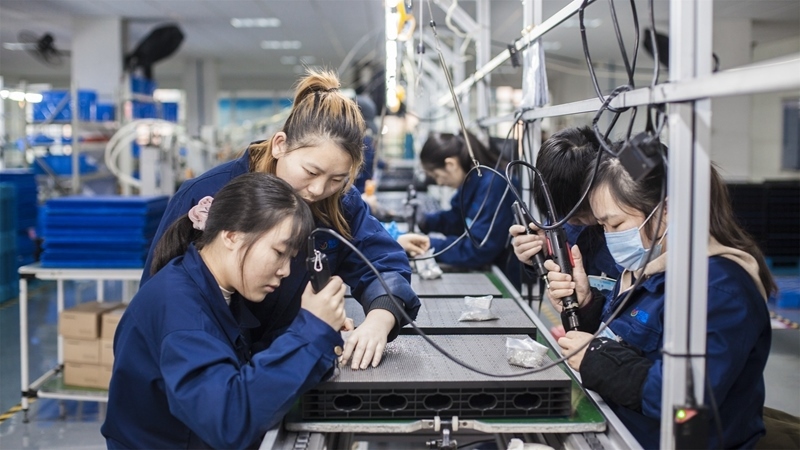 在新亞勝光電的產(chǎn)品線上，工人正進行產(chǎn)品組建和安裝布線。受訪者供圖