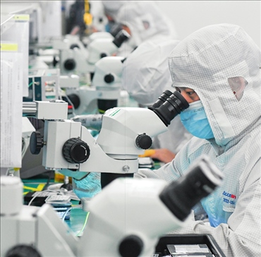 在位于武漢中國(guó)光谷的光電器件研發(fā)制造商——武漢光迅科技股份有限公司生產(chǎn)車間內(nèi)，技術(shù)人員在光模塊生產(chǎn)線作業(yè)（2023年4月11日攝）。程敏攝/本刊