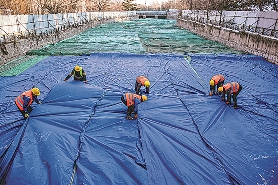 1月3日，房山區(qū)東風(fēng)街道，工人正在修復(fù)的河道內(nèi)給混凝土鋪設(shè)保溫布。