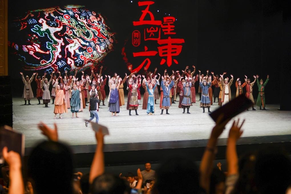 2023年7月31日，新疆和田地區(qū)新玉歌舞團在烏魯木齊京劇院演出舞劇《五星出東方》后和觀眾互相揮手致意。這場演出是第六屆中國新疆國際民族舞蹈節(jié)的參演劇目之一，曾榮獲國家“文華獎”等。新華社記者 郝昭 攝