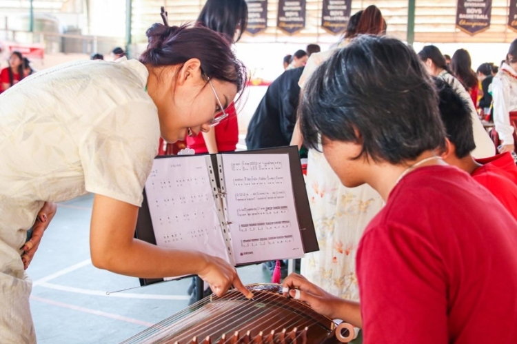 志愿者教師指導(dǎo)學(xué)生彈奏古箏。活動(dòng)主辦方供圖