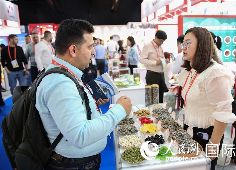 圖為一家中國(guó)干果參展企業(yè)代表與采購(gòu)商洽談。人民網(wǎng) 塔里克·易卜拉欣攝