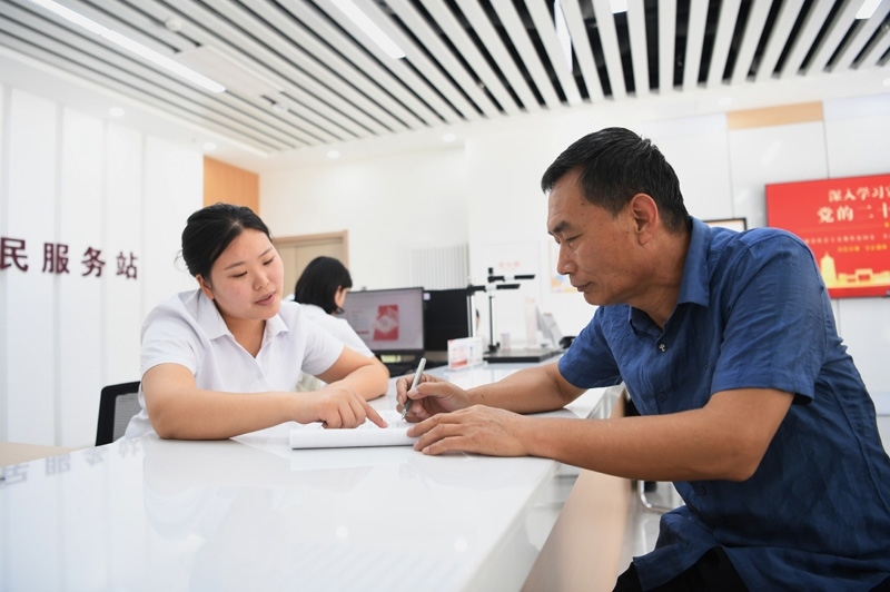 2023年5月23日，河北雄安新區(qū)容東片區(qū)南文營社區(qū)居民（右）在社區(qū)便民服務(wù)站辦理業(yè)務(wù)。
