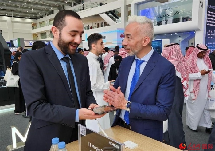 兩名觀眾在榮耀手機展臺前交流。人民網(wǎng)記者 管克江攝