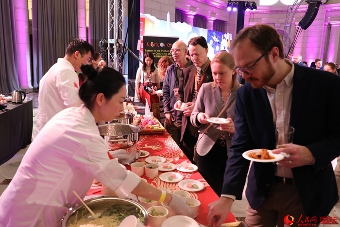 當(dāng)?shù)貢r(shí)間3月7日晚，華盛頓聯(lián)合車站廣場舉行駐美使團(tuán)“使館主廚挑戰(zhàn)賽”。圖為當(dāng)?shù)孛癖娫谥袊古_(tái)前體驗(yàn)中國美食。人民網(wǎng)記者 李志偉攝