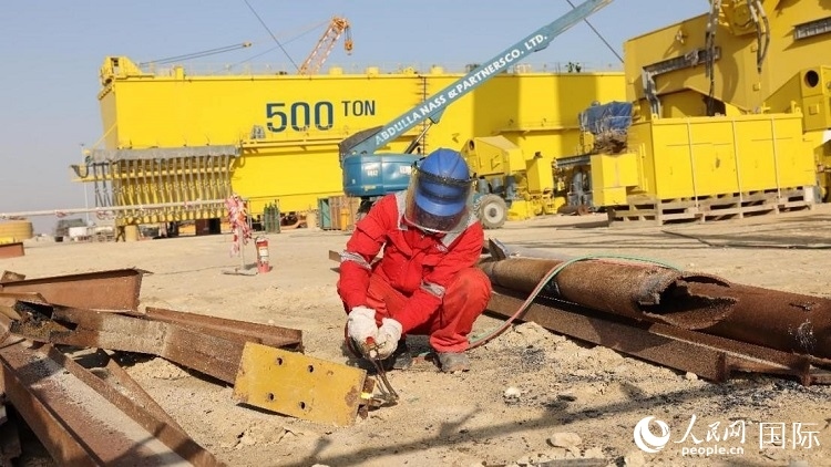 工人正在龍門吊吊裝現(xiàn)場(chǎng)切割金屬件。人民網(wǎng)記者管克江攝