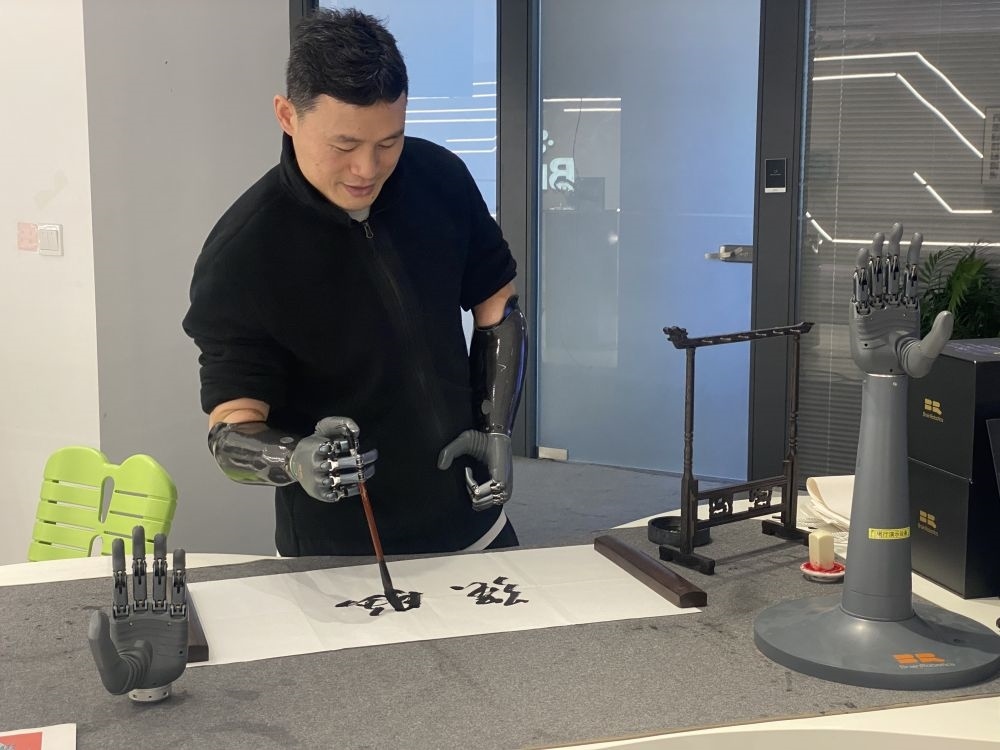 2024年3月29日，在浙江強(qiáng)腦科技有限公司展廳內(nèi)，失去雙手的產(chǎn)品體驗(yàn)官倪敏成依靠智能仿生手寫毛筆字。新華社記者 魏一駿 攝