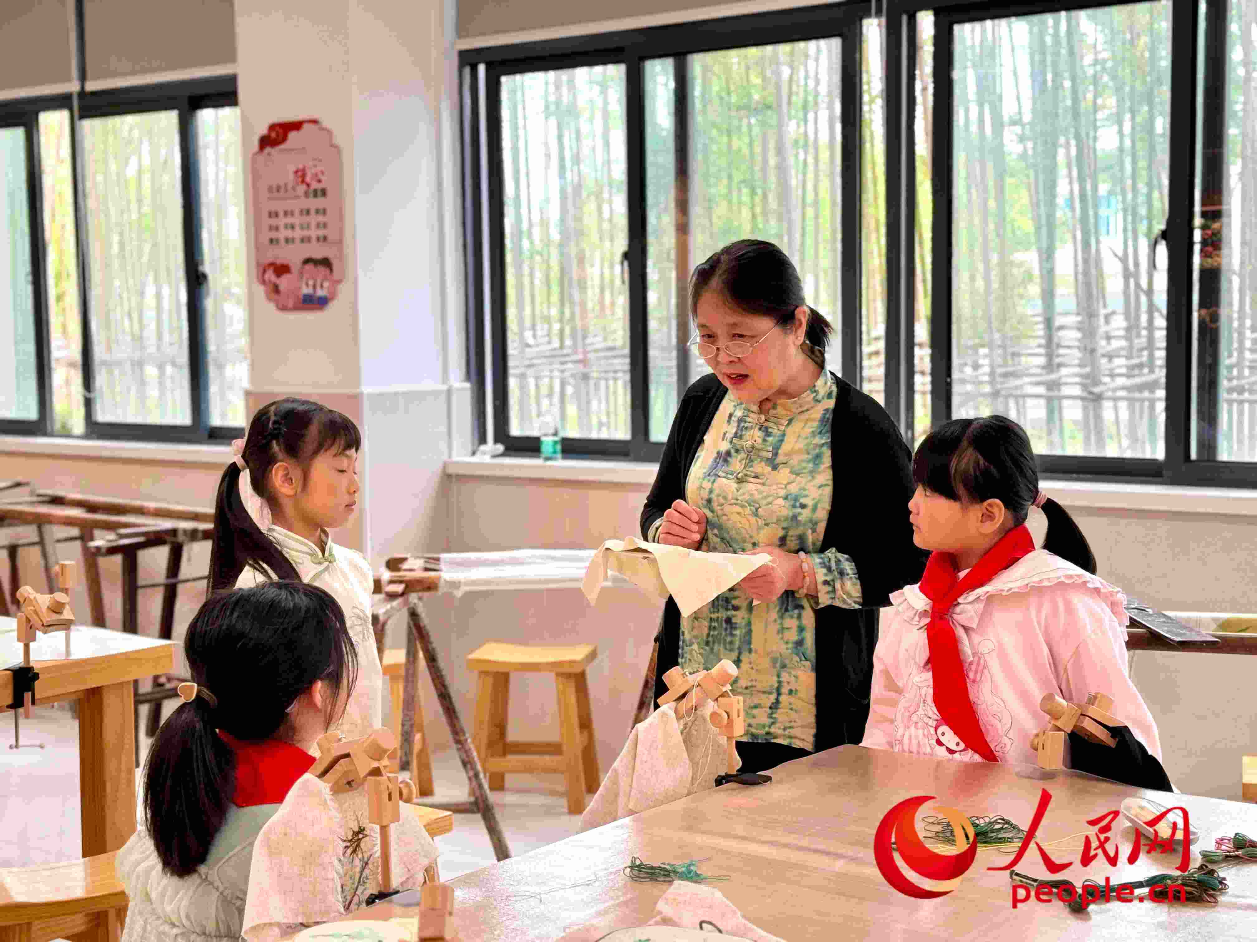 顧建珍（左三）在教孩子們刺繡知識。人民網(wǎng) 周靜圓攝