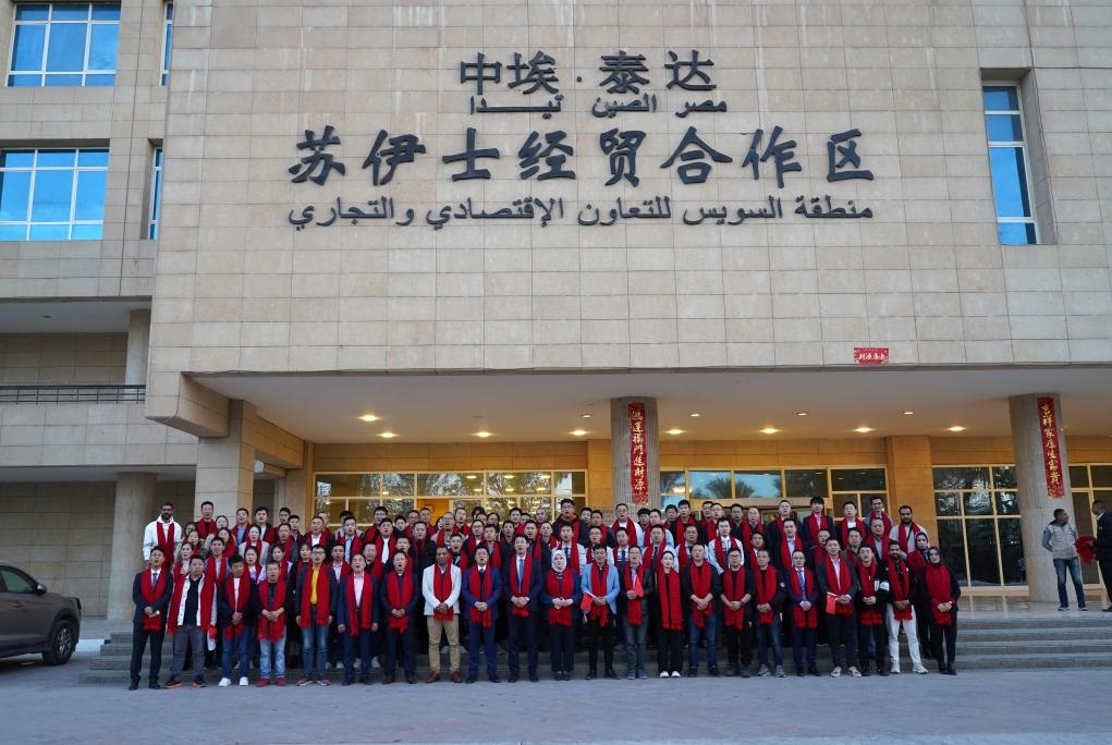 2024年2月11日，在位于埃及蘇伊士省的中?！ぬ┻_(dá)蘇伊士經(jīng)貿(mào)合作區(qū)，中埃員工在合作區(qū)辦公大樓前合影拜年。新華社發(fā)（泰達(dá)合作區(qū)供圖）