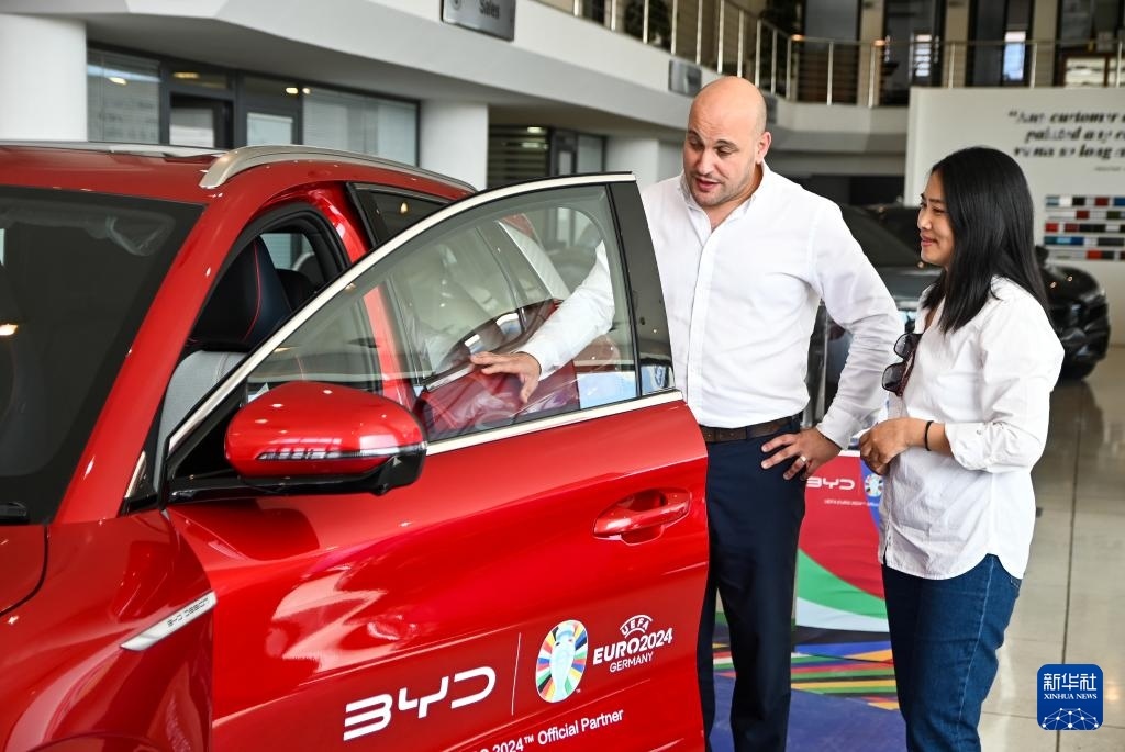 2024年5月29日，在馬耳他比爾基卡拉，馬耳他哈桑-扎米特汽車公司首席執(zhí)行官德古阿拉（左）介紹一輛比亞迪純電動汽車。新華社發(fā)（喬納森·博格 攝）