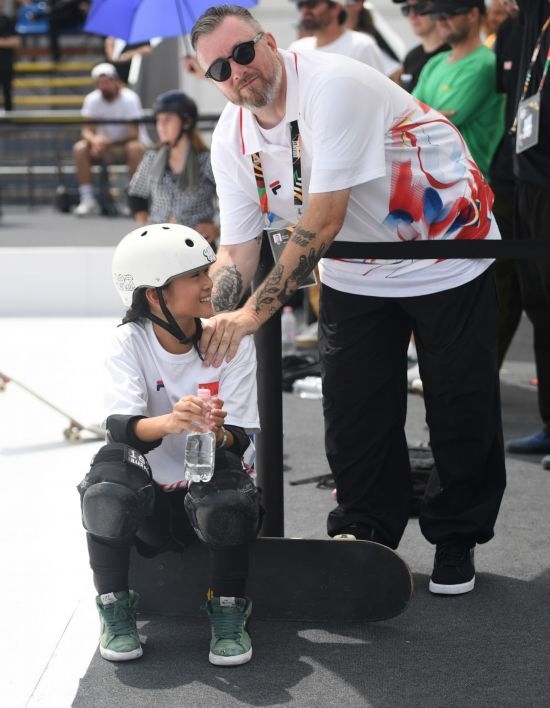 6月20日，鄭好好（左）在比賽間隙與教練互動，她在預賽中最佳成績?yōu)?2.60分。當日，巴黎奧運會資格系列賽布達佩斯站滑板女子碗池預賽在布達佩斯舉行。新華社記者 賀燦鈴 攝