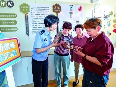 浙江湖州民警指導(dǎo)居民加入湖州“e企安”微信群，實時接收反詐信息。新華社發(fā)