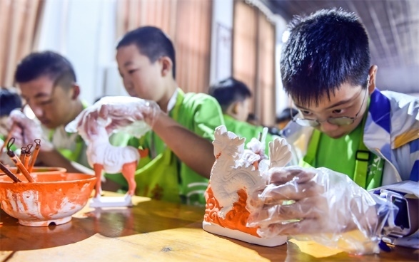 小朋友們在洛陽市孟津區(qū)朝陽鎮(zhèn)南石山村體驗唐三彩素胎施釉技藝。圖片來源：視覺中國