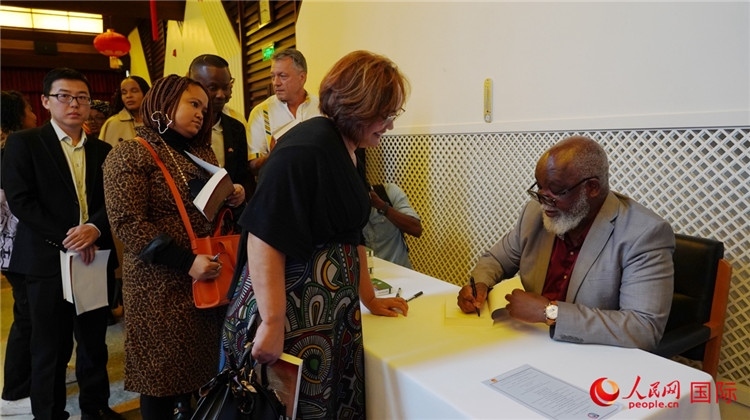 譚哲理在活動現(xiàn)場簽名贈書。人民網(wǎng) 劉暢攝