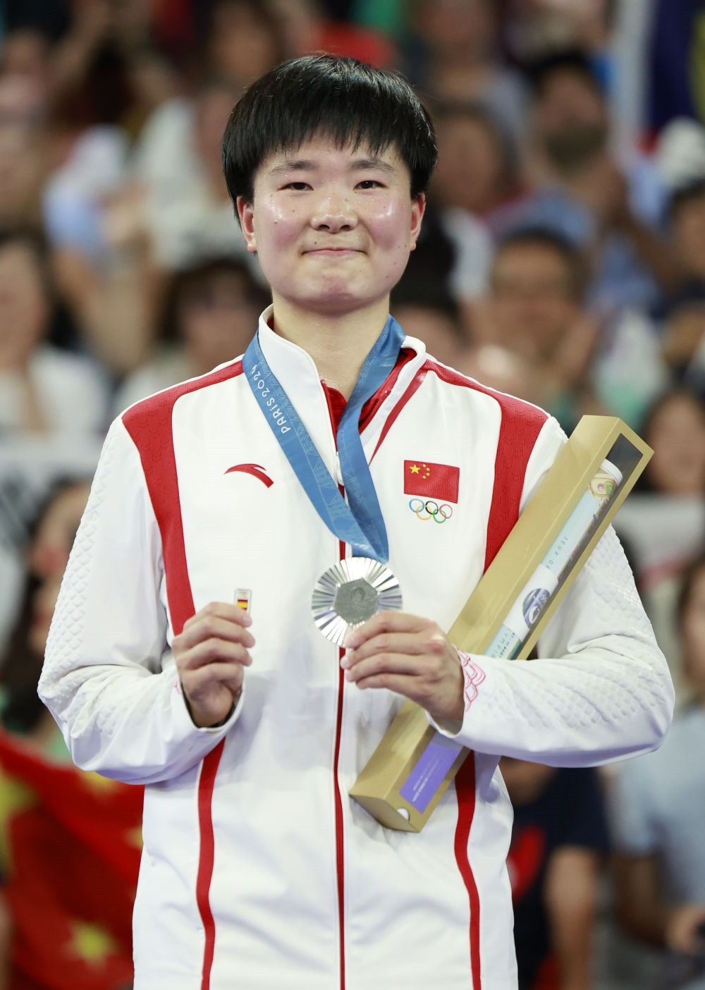 巴黎奧運會羽毛球女子單打亞軍、中國選手何冰嬌在頒獎儀式上一手握著銀牌，一手握著西班牙奧委會徽章（2024年8月5日攝）。新華社記者 任正來 攝