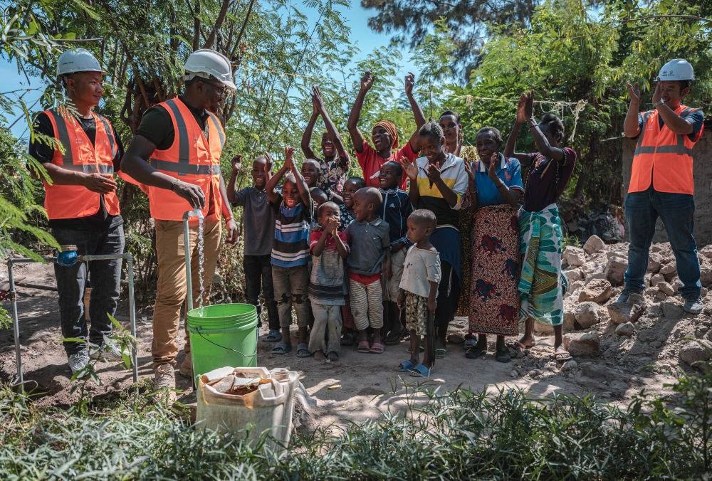 2023年6月13日，在坦桑尼亞姆萬(wàn)扎省米松圭，工作人員接通水管后贏得當(dāng)?shù)鼐用窆恼茪g呼。新華社記者 王冠森 攝