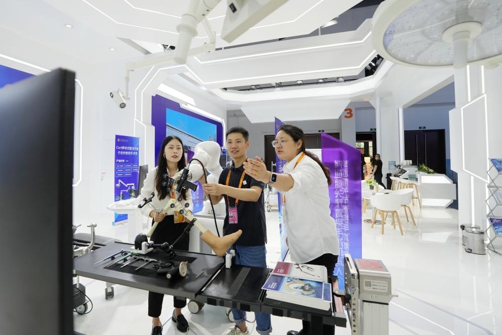 9月11日，一位媒體記者（中）在2024年服貿(mào)會國家會議中心會場體驗北京納通科技集團有限公司的膝關(guān)節(jié)置換手術(shù)機器人。新華社記者鞠煥宗 攝