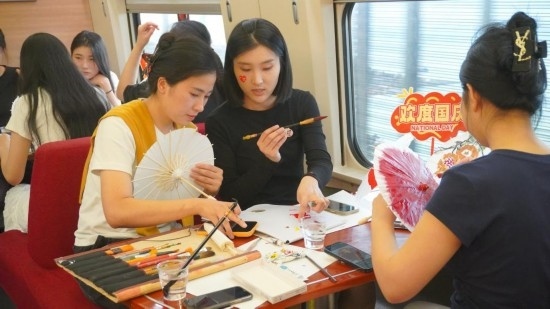 10月1日，旅客們在G1634次列車上給油紙傘作畫。新華社記者周義 攝