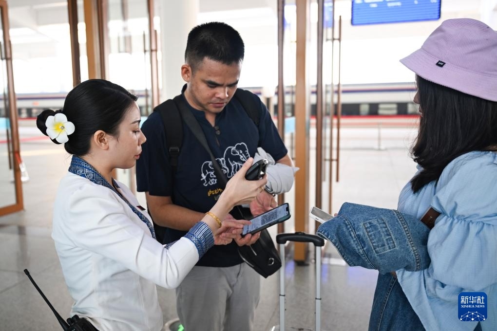 10月12日，在老撾萬象中老鐵路萬象站，工作人員檢驗(yàn)乘客車票。新華社記者 程一恒 攝