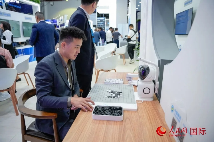 觀眾在中國移動國際有限公司展臺體驗智慧圍棋機器人。人民網(wǎng) 塔里克·易卜拉欣攝