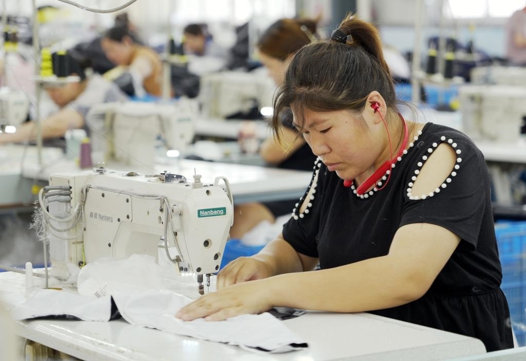5月20日，村民在李寨村服裝加工廠內(nèi)忙碌。河南省周口市沈丘縣馮營(yíng)鎮(zhèn)李寨村地處豫東平原。近年來，乘著脫貧攻堅(jiān)與鄉(xiāng)村振興政策的東風(fēng)，李寨村積極探索產(chǎn)業(yè)發(fā)展模式，通過“龍頭企業(yè)+村集體經(jīng)濟(jì)+農(nóng)戶”的方式，逐漸發(fā)展形成肉牛養(yǎng)殖、設(shè)施農(nóng)業(yè)、服裝加工、康養(yǎng)民宿等產(chǎn)業(yè)，以產(chǎn)業(yè)振興助力鄉(xiāng)村振興。新華社記者 李嘉南 攝