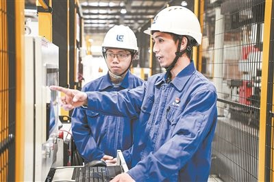 在廣西柳工機(jī)械股份有限公司生產(chǎn)車(chē)間內(nèi)，一名高級(jí)技師（右）給徒弟講解數(shù)控設(shè)備操作細(xì)節(jié)。新華社記者 曹祎銘攝