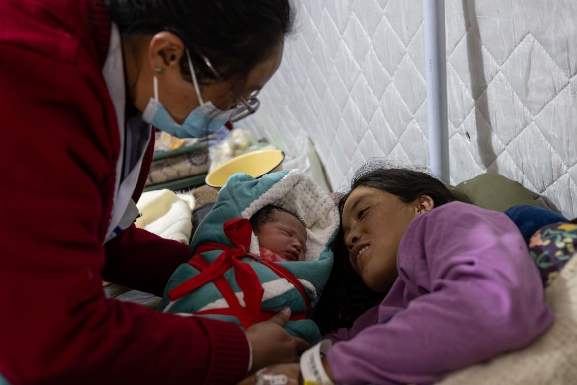 1月10日，定日縣中心醫(yī)院的婦產(chǎn)科醫(yī)生悉心照看一位母親和她懷里的新生兒。人民日?qǐng)?bào)記者張武軍攝