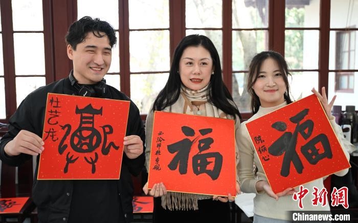 1月20日，外籍留學(xué)生和西泠印社社員李硯(中)展示各自創(chuàng)作的福貼。當(dāng)日，來(lái)自巴西、馬來(lái)西亞、加納、哈薩克斯坦的外籍留學(xué)生在浙江杭州西泠印社體驗(yàn)福貼、春聯(lián)和篆刻，感受古老的中國(guó)傳統(tǒng)文化。中新社記者 王剛 攝