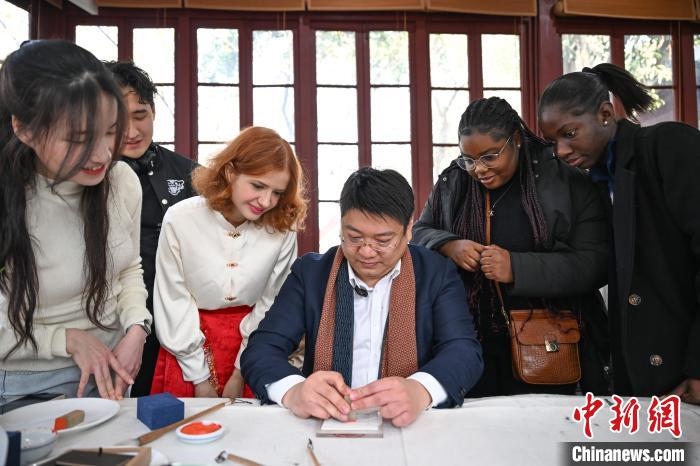1月20日，篆刻家王臻向外籍留學(xué)生展示篆刻印章。當(dāng)日，來(lái)自巴西、馬來(lái)西亞、加納、哈薩克斯坦的外籍留學(xué)生在浙江杭州西泠印社體驗(yàn)福貼、春聯(lián)和篆刻，感受古老的中國(guó)傳統(tǒng)文化。中新社記者 王剛 攝