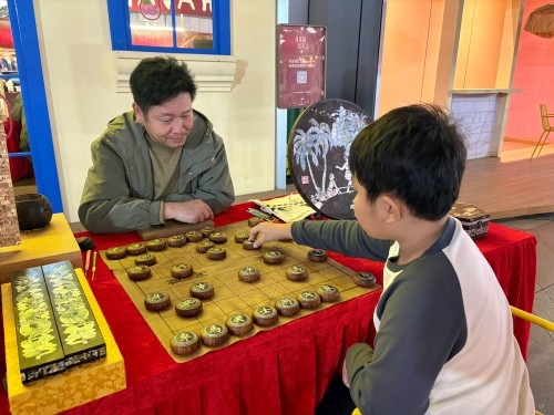 柯秋楓與市民下椰雕象棋。人民網(wǎng) 陳葉欣攝